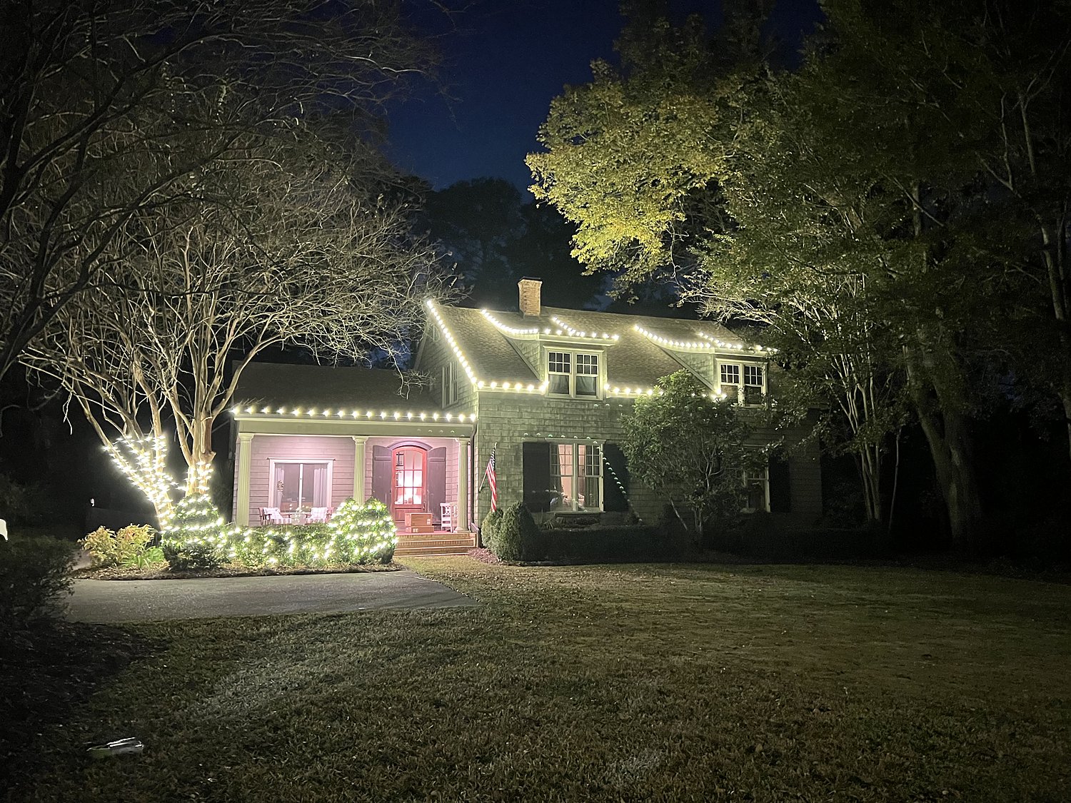 Two-story home with warm white roofline Christmas lighting
