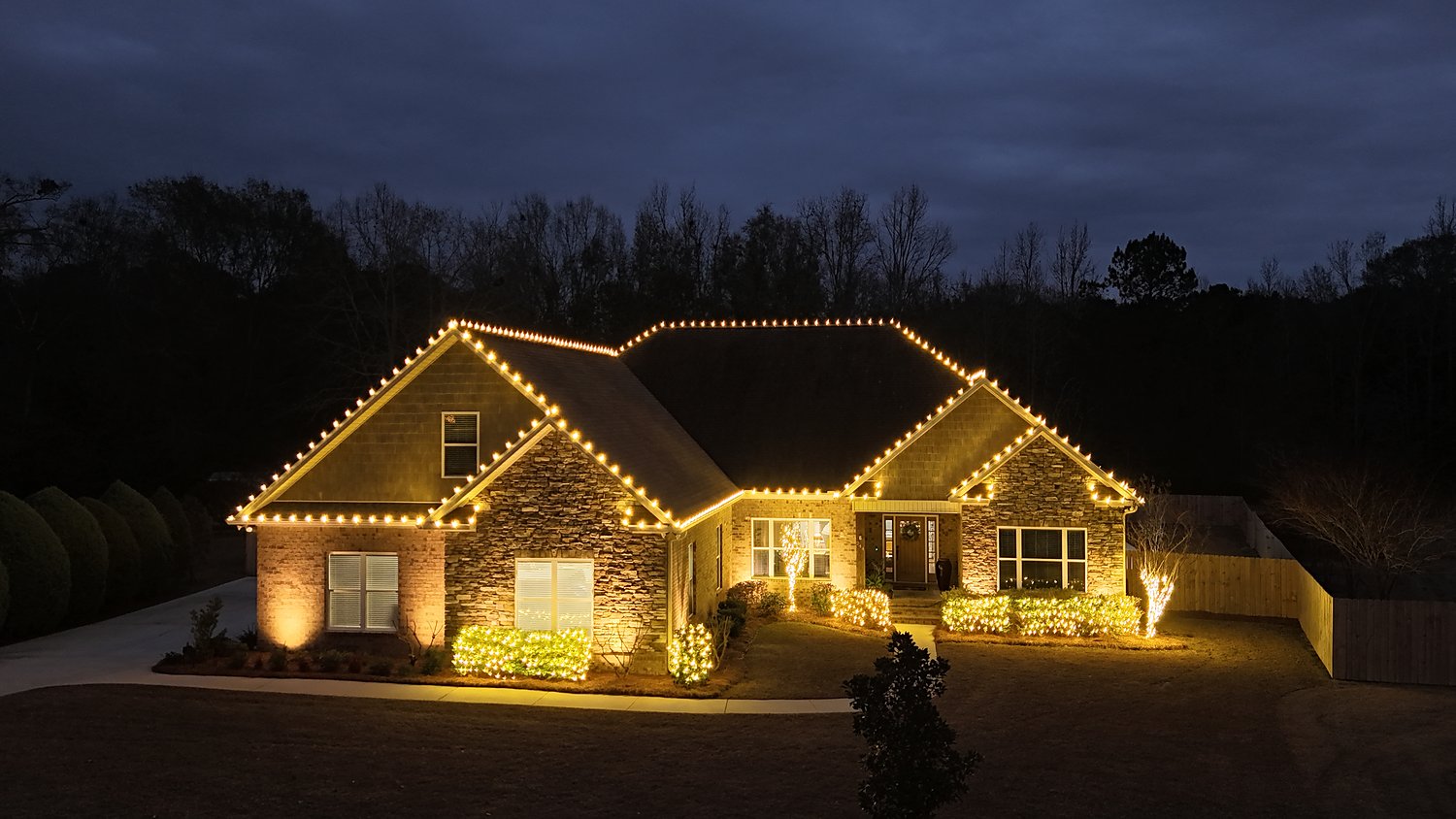 Aerial view of a fully lit home and landscaping at night